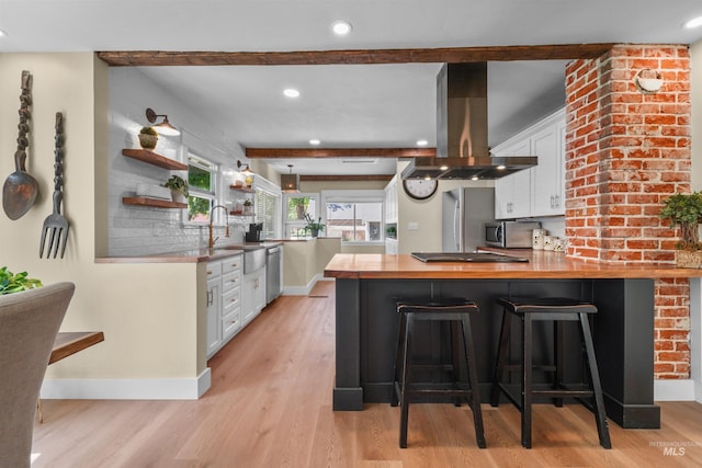 1924 Cleveland Blvd, Caldwell, ID 83605 - kitchen with island exhaust hood, white cabinets, appliances with stainless steel finishes, light wood-type flooring, and a peninsula
