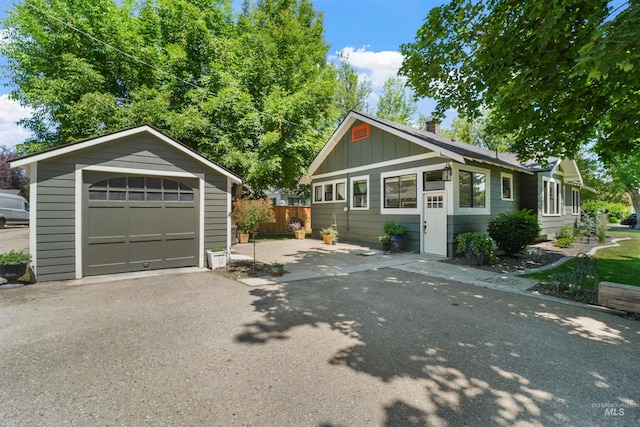 1924 Cleveland Blvd, Caldwell, ID 83605 - view of front of property featuring an outdoor structure, a garage, asphalt driveway, board and batten siding, and a chimney