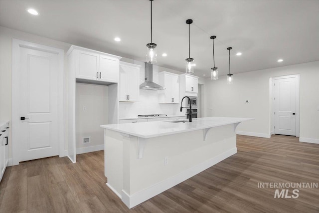 5801 W Escalante, Eagle, ID 83616 - kitchen with wall chimney range hood, white cabinetry, a kitchen island with sink, light countertops, and a sink
