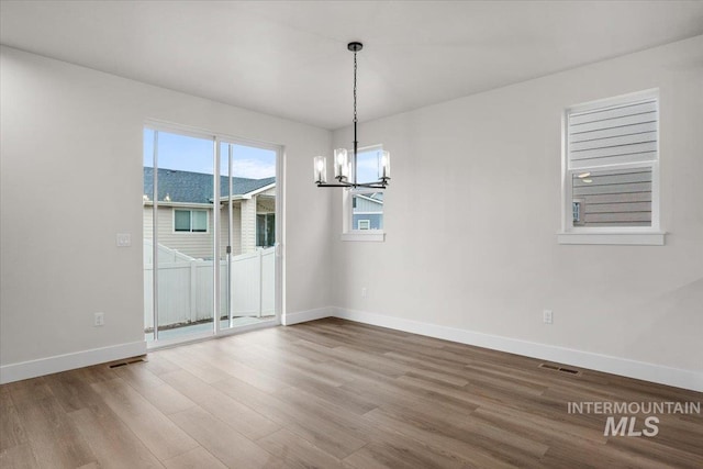 5801 W Escalante, Eagle, ID 83616 - unfurnished dining area featuring a notable chandelier, baseboards, visible vents, and wood finished floors