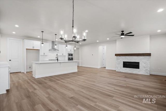 5801 W Escalante, Eagle, ID 83616 - unfurnished living room featuring light wood-style floors, ceiling fan with notable chandelier, a fireplace, recessed lighting, and baseboards