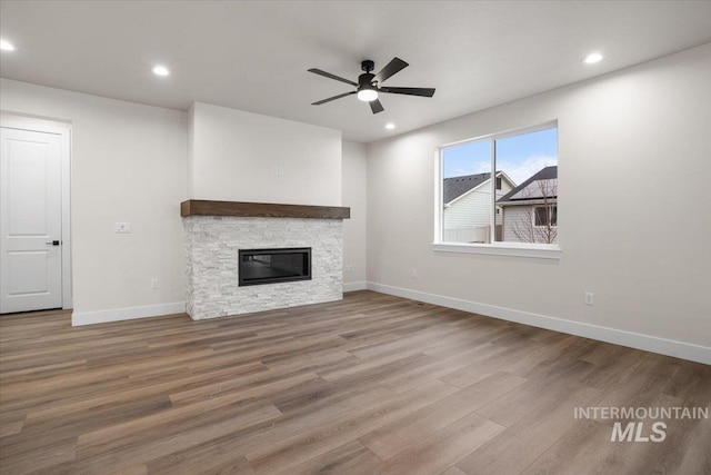 5801 W Escalante, Eagle, ID 83616 - unfurnished living room featuring wood finished floors, ceiling fan, a stone fireplace, and recessed lighting