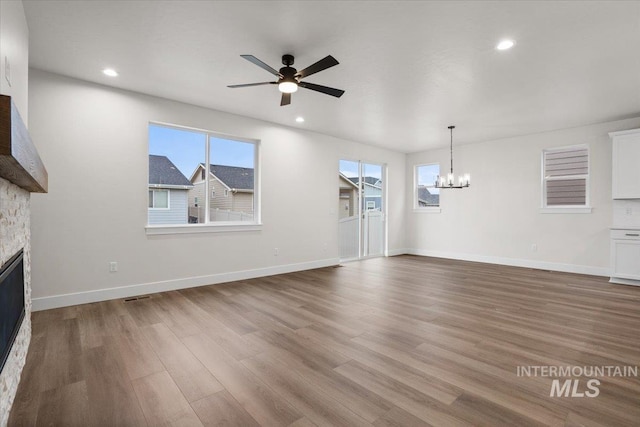 5801 W Escalante, Eagle, ID 83616 - unfurnished living room with ceiling fan with notable chandelier, wood finished floors, baseboards, and a stone fireplace