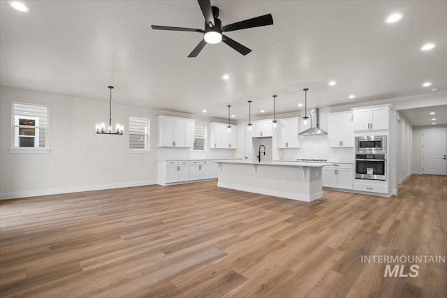 5801 W Escalante, Eagle, ID 83616 - kitchen featuring light wood-style floors, a kitchen breakfast bar, wall chimney range hood, appliances with stainless steel finishes, and a sink