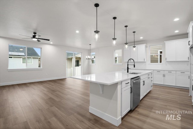 5801 W Escalante, Eagle, ID 83616 - kitchen with light wood-style floors, ceiling fan with notable chandelier, dishwasher, a sink, and a center island with sink