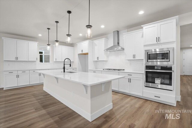 5801 W Escalante, Eagle, ID 83616 - kitchen featuring wall chimney range hood, wood finished floors, a sink, and appliances with stainless steel finishes