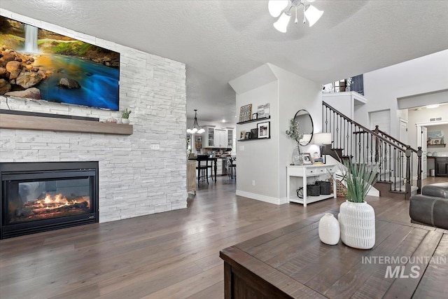 living room with stairs, a fireplace, a textured ceiling, and wood finished floors