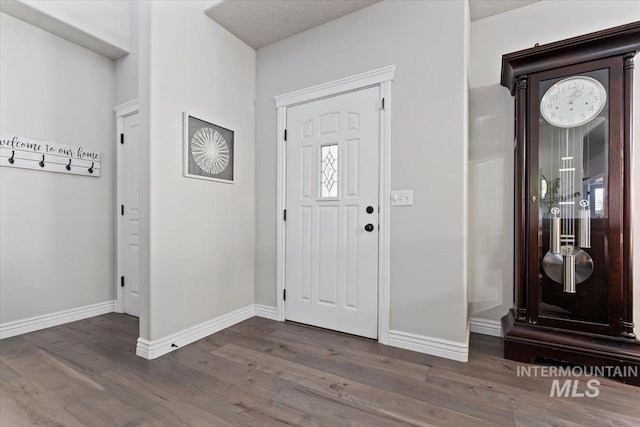 entryway with dark wood-type flooring and baseboards