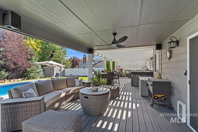 wooden terrace featuring an outbuilding, ceiling fan, an outdoor living space, a storage unit, and outdoor dining space