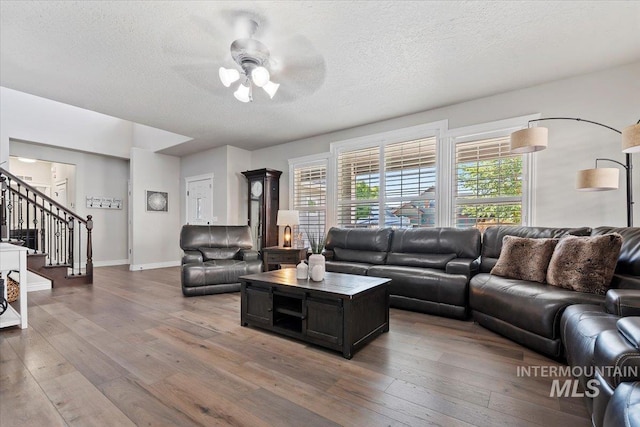 living room with stairs, ceiling fan, a textured ceiling, and wood finished floors