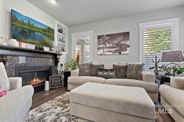 living room featuring dark wood-type flooring, a textured ceiling, and a premium fireplace