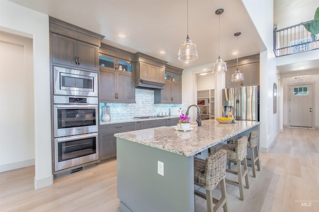 2649 E Mardia St, Meridian, ID 83642 - kitchen with appliances with stainless steel finishes, baseboards, light wood finished floors, a breakfast bar, and recessed lighting
