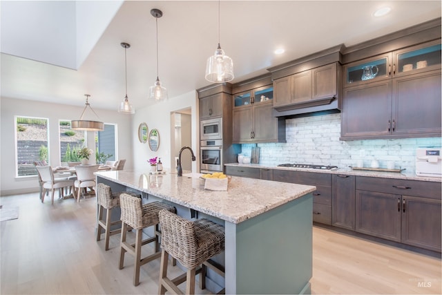 2649 E Mardia St, Meridian, ID 83642 - kitchen featuring stainless steel appliances, light wood-style floors, a breakfast bar, decorative backsplash, and light stone countertops