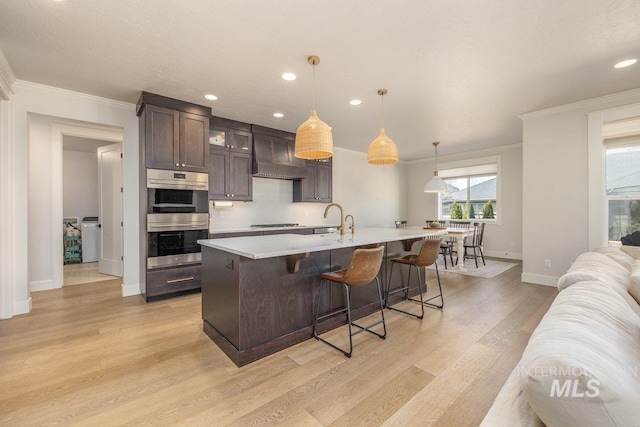 kitchen featuring double oven, black cooktop, light countertops, wall chimney range hood, and dark brown cabinets