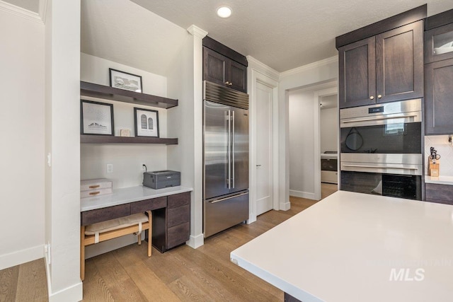 kitchen featuring stainless steel appliances, light wood finished floors, light countertops, and dark brown cabinetry