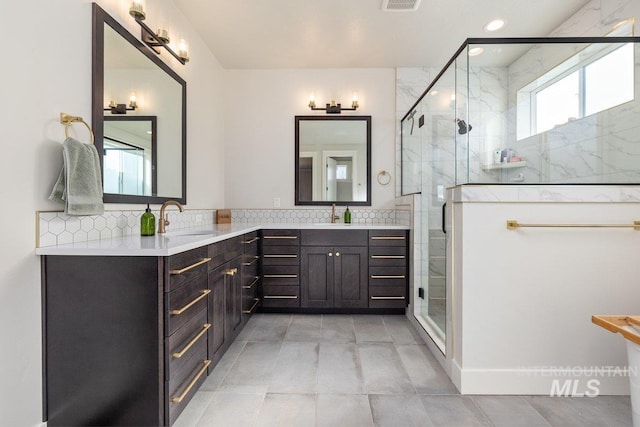 bathroom featuring a stall shower, vanity, visible vents, and decorative backsplash