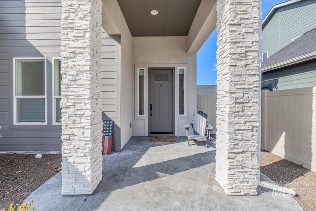 doorway to property with fence and stucco siding