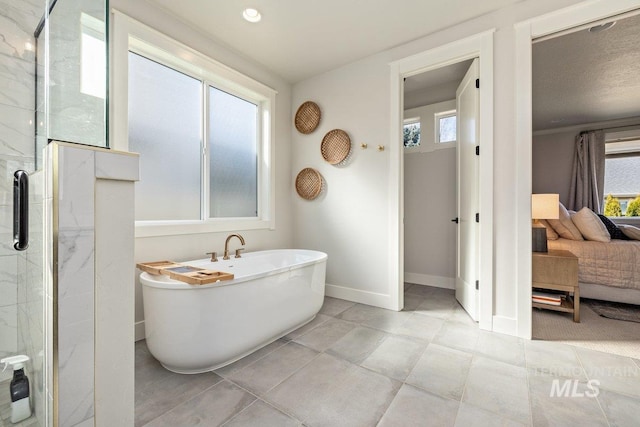 full bath with a freestanding bath, ensuite bath, a shower with shower door, and baseboards