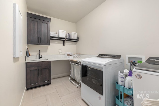 laundry room with a sink, cabinet space, baseboards, and washer and dryer