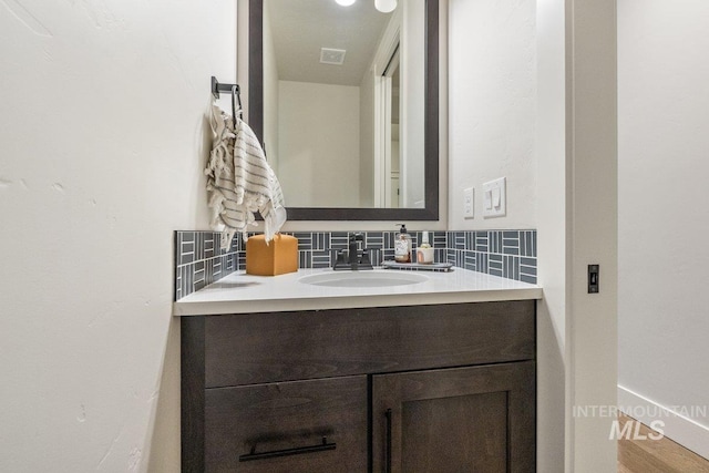 bathroom with tasteful backsplash, visible vents, vanity, and baseboards