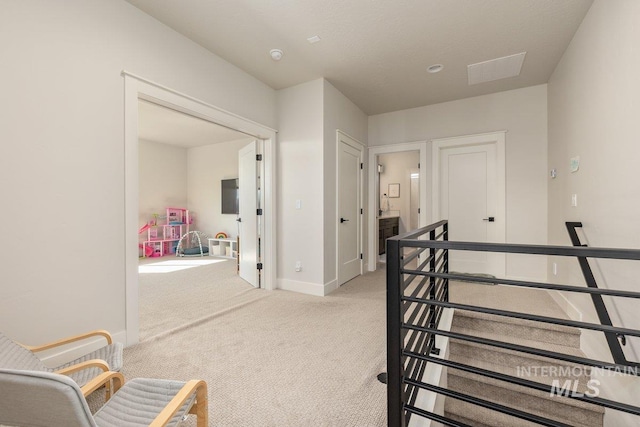 corridor featuring carpet floors, baseboards, and an upstairs landing