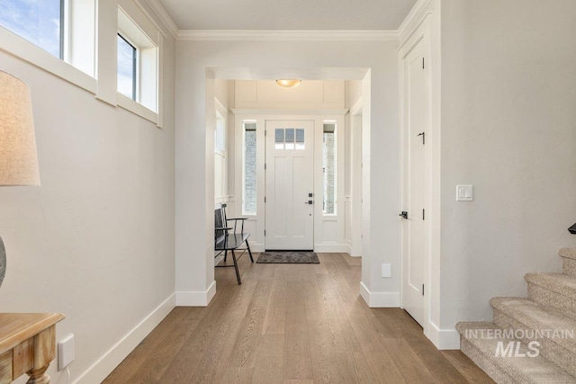 entrance foyer with baseboards, stairway, wood finished floors, and crown molding