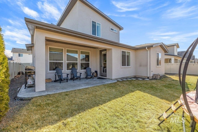 back of house with a patio, a lawn, a fenced backyard, and stucco siding