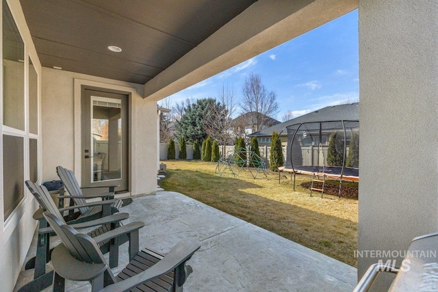 view of patio / terrace featuring a trampoline, a playground, and fence