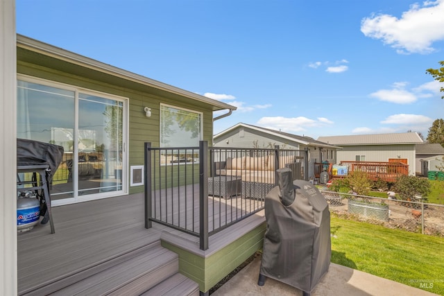 wooden deck featuring fence, a yard, and a grill