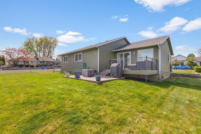 back of property featuring a wooden deck, a yard, a patio, and fence