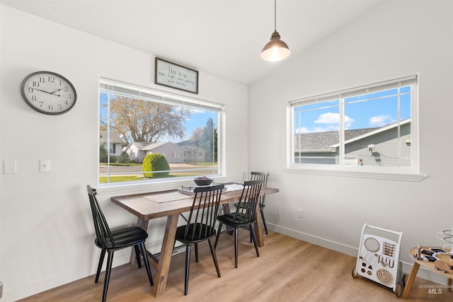 dining area with vaulted ceiling, light wood finished floors, and baseboards