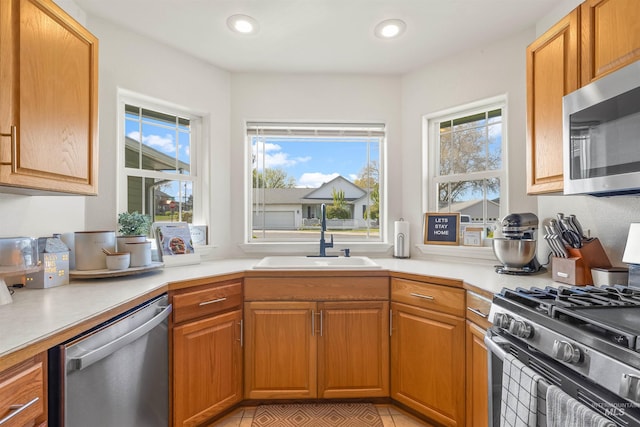 kitchen with a wealth of natural light, appliances with stainless steel finishes, light tile patterned floors, and a sink