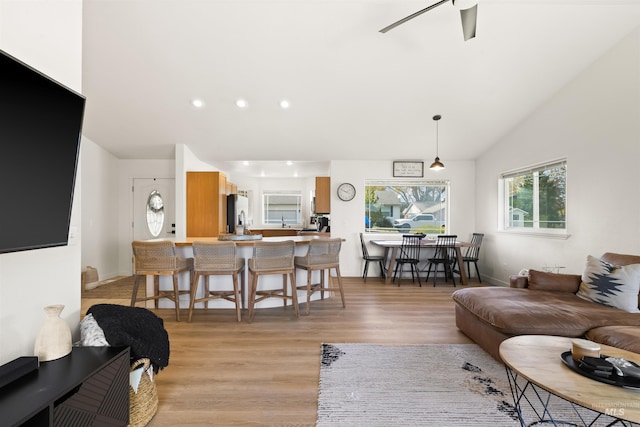 living area with vaulted ceiling, a ceiling fan, light wood-style floors, baseboards, and recessed lighting