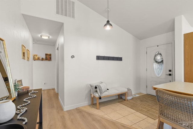 foyer entrance featuring light wood-type flooring, baseboards, visible vents, and lofted ceiling