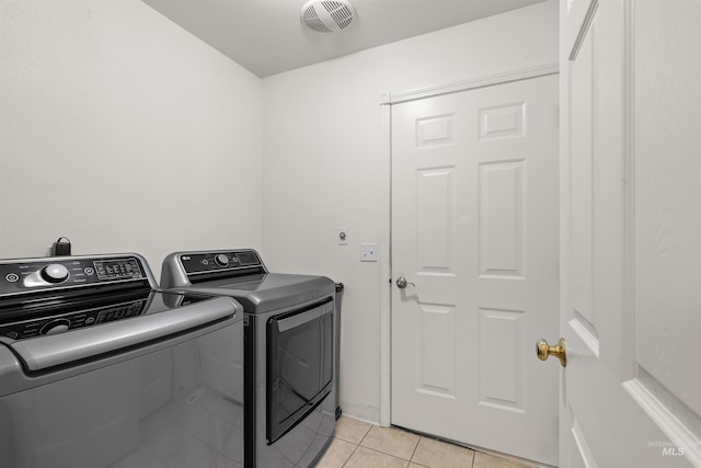 clothes washing area featuring visible vents, washer and clothes dryer, laundry area, and light tile patterned floors