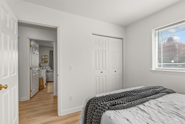 bedroom with baseboards, a closet, and light wood-style flooring