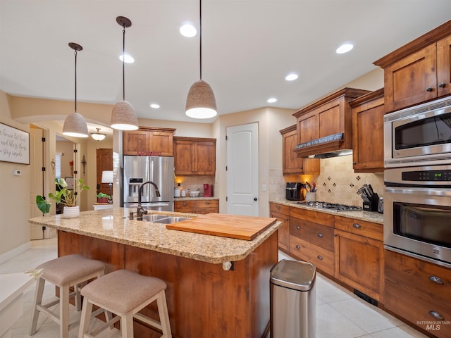 kitchen featuring pendant lighting, sink, stainless steel appliances, and an island with sink