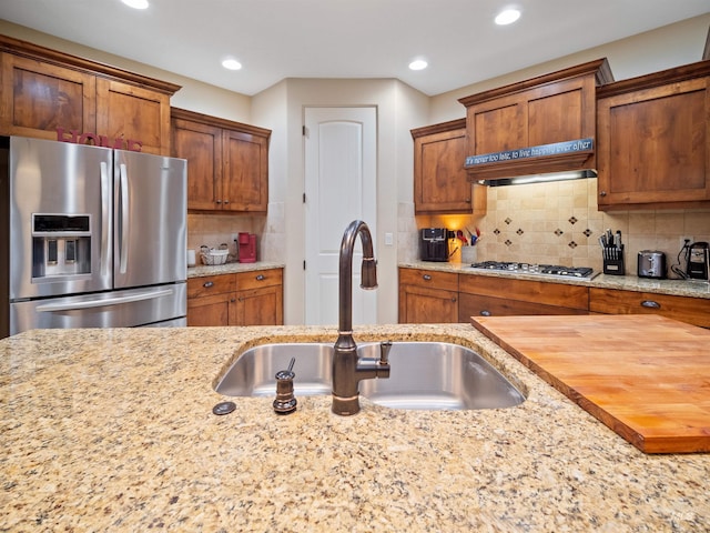 kitchen featuring sink, wooden counters, premium range hood, appliances with stainless steel finishes, and tasteful backsplash