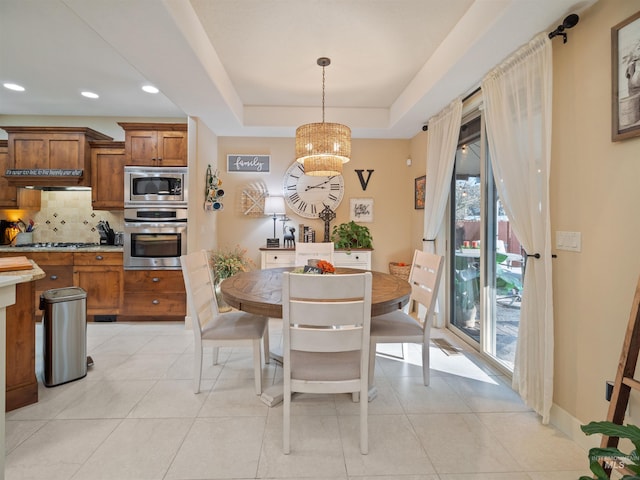 tiled dining area with a notable chandelier and a tray ceiling