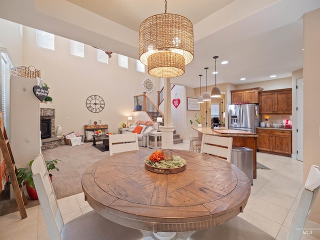 dining room with a notable chandelier, a stone fireplace, and light tile patterned floors