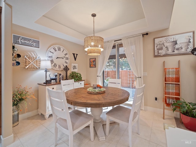 dining room with light tile patterned flooring and a raised ceiling