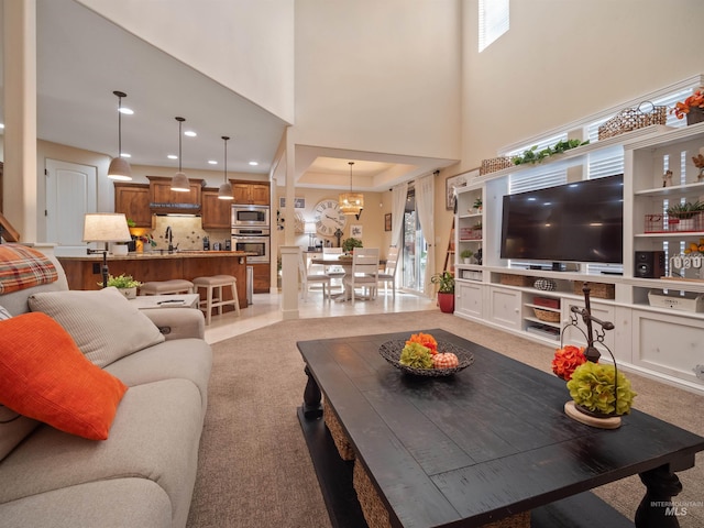 living room with a towering ceiling, a chandelier, and sink