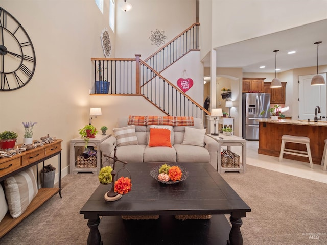 carpeted living room featuring a towering ceiling and sink