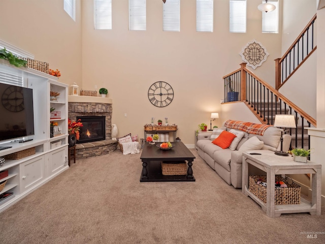 carpeted living room with a high ceiling, a stone fireplace, and a wealth of natural light