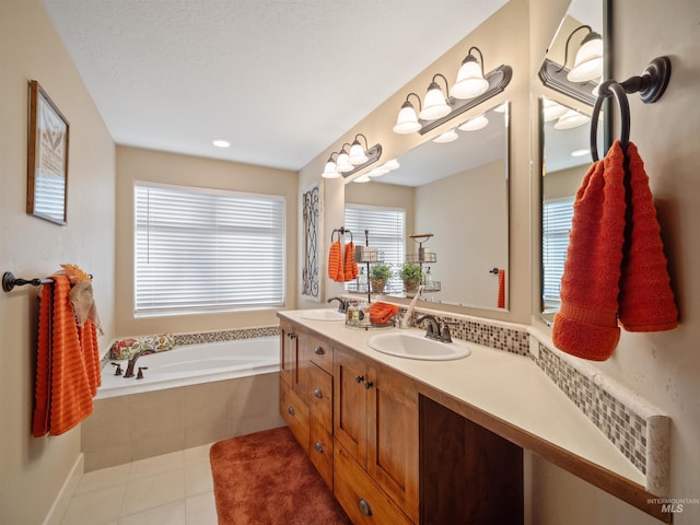 bathroom featuring tile patterned floors, a textured ceiling, vanity, and tiled tub