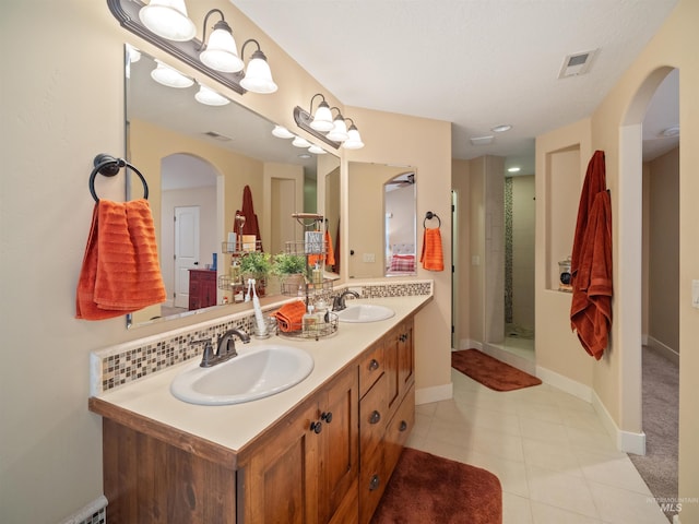 bathroom with vanity, tile patterned flooring, decorative backsplash, and walk in shower