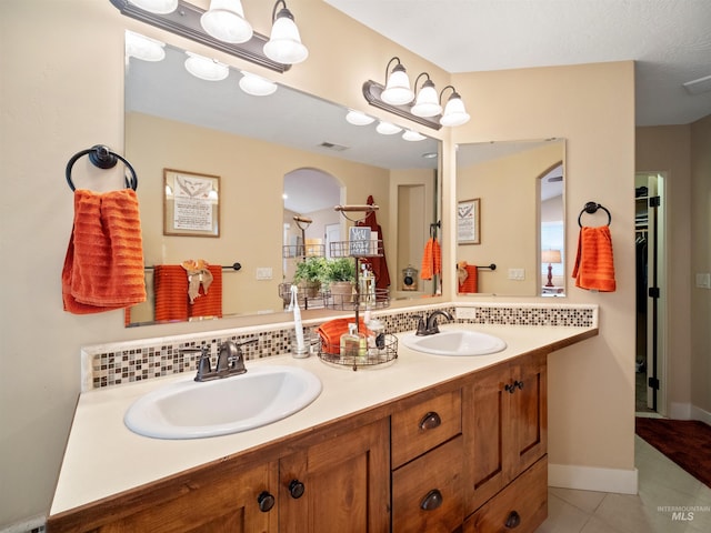 bathroom featuring tile patterned flooring, vanity, and tasteful backsplash