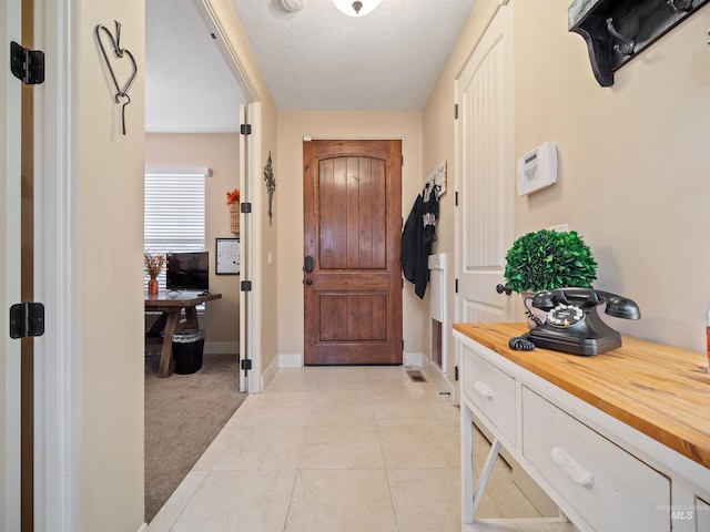 entryway featuring light colored carpet and a textured ceiling