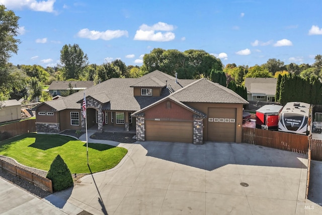 view of front facade featuring a shingled roof, fence, a garage, driveway, and a front lawn