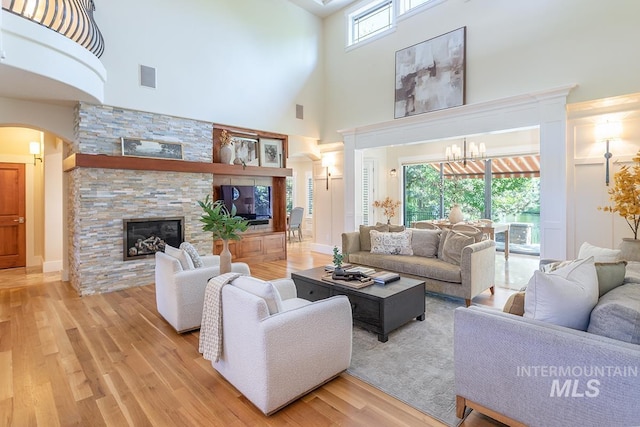 1049 E Riversong Dr, Eagle, ID 83616 - living room with a towering ceiling, arched walkways, wood finished floors, a stone fireplace, and a chandelier